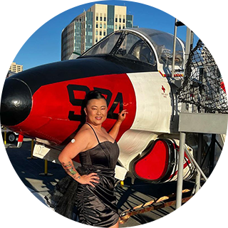 A woman wearing a sensor while standing in front of a prop plane.