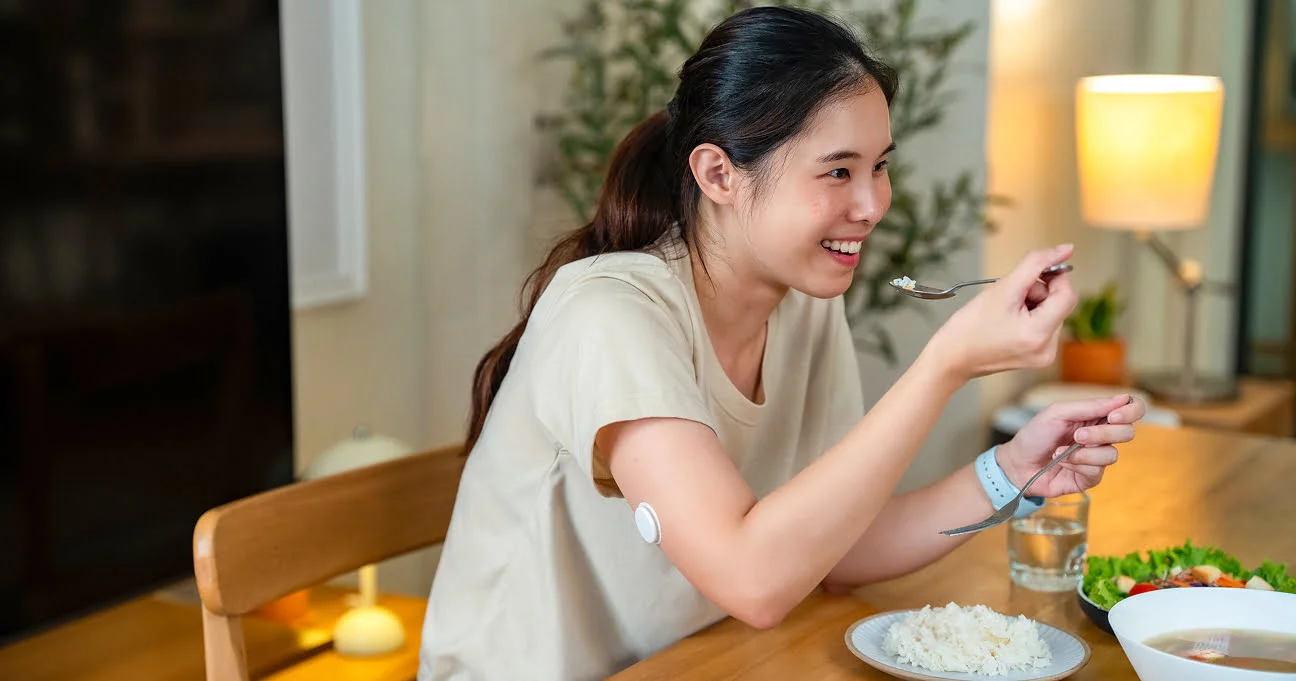  Một người phụ nữ đeo thiết bị theo dõi nhịp tim FreeStyle Libre đang thưởng thức bữa ăn lành mạnh tại nhà.