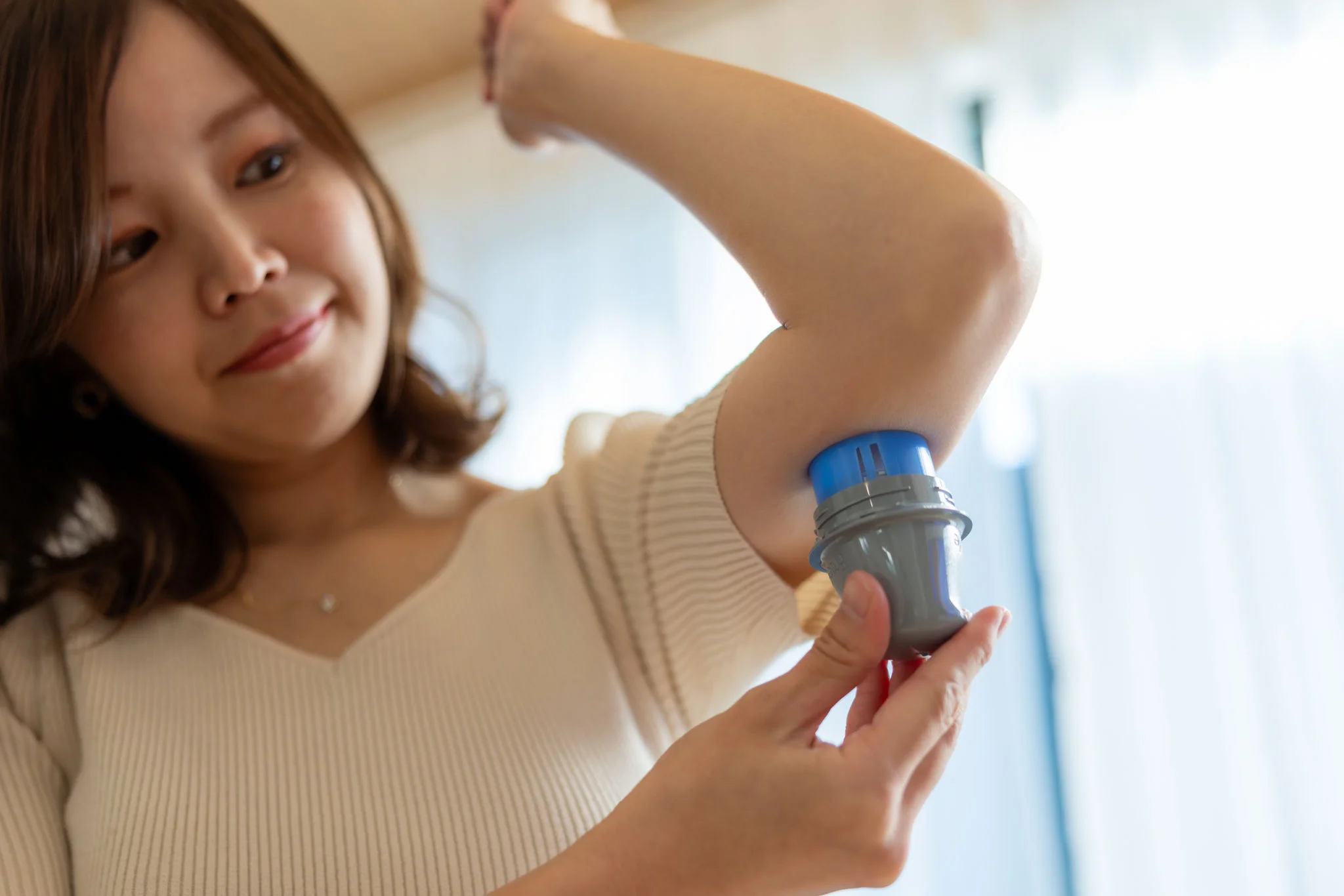 Mulher aplicando o sensor FreeStyle Libre na parte posterior do braço.