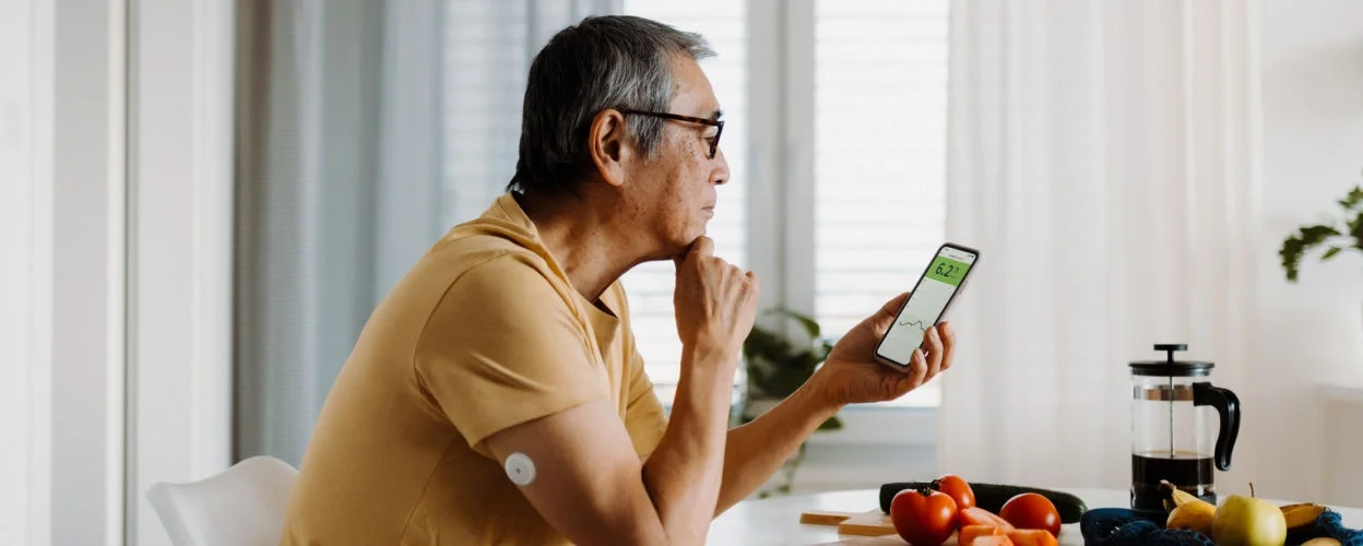 man reading glucose data on smartphone