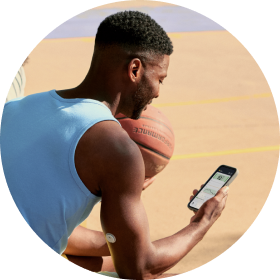 Man with a basketball staring at his phone while wearing a FreeStyle Libre 3 Plus sensor