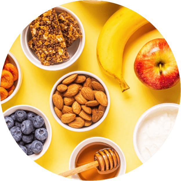 Frutas, frutos secos y miel dispuestos en tazones sobre una mesa amarilla, ejemplo de aperitivos naturales y equilibrados.