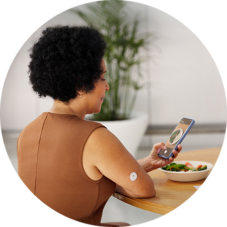 Woman taking a photo of her meal while wearing a FreeStyle Libre 3 Plus sensor