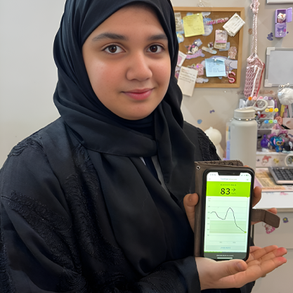 Woman holding mobile phone with glucose trend on screen