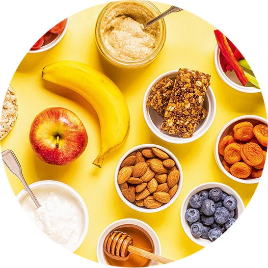 Assortment of healthy snack options including fruit, nuts, yogurt, hummus, granola bars, and blueberries.