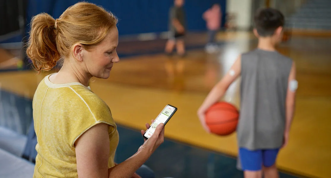 Woman checking her child’s FreeStyle Libre 3 Plus sensor