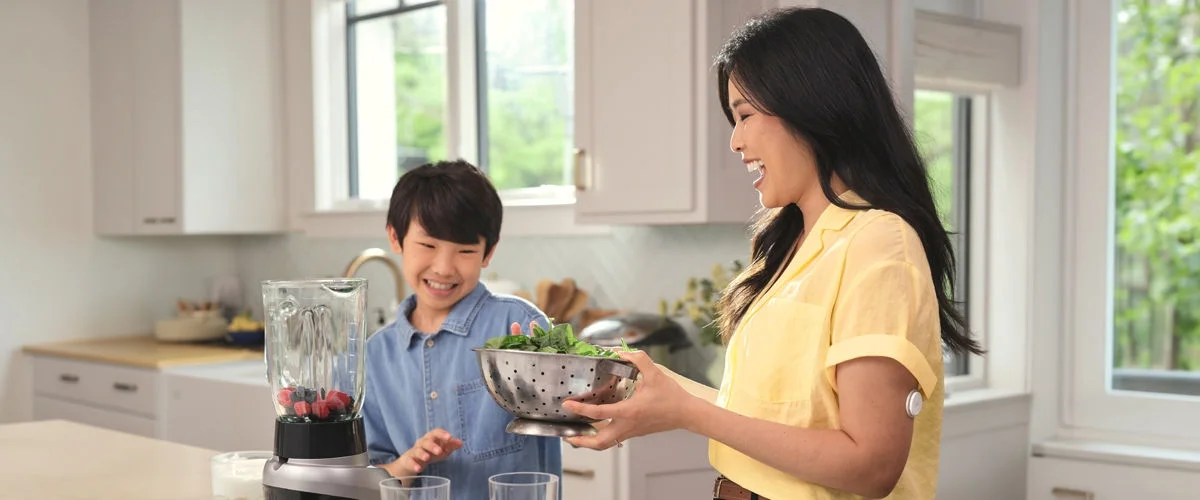 A grandmother cooks with her granddaughter in a bright kitchen, with a FreeStyle Libre sensor on her upper arm.
