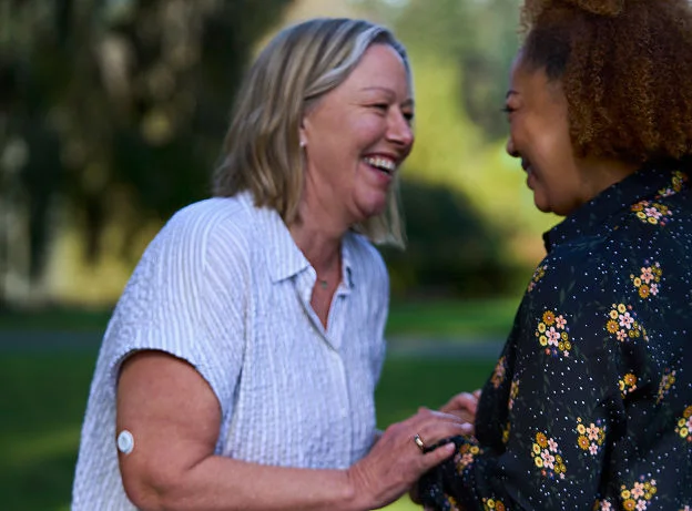 Two women laughing together in a community setting, great for boosting mental health positivity and reducing stress levels.