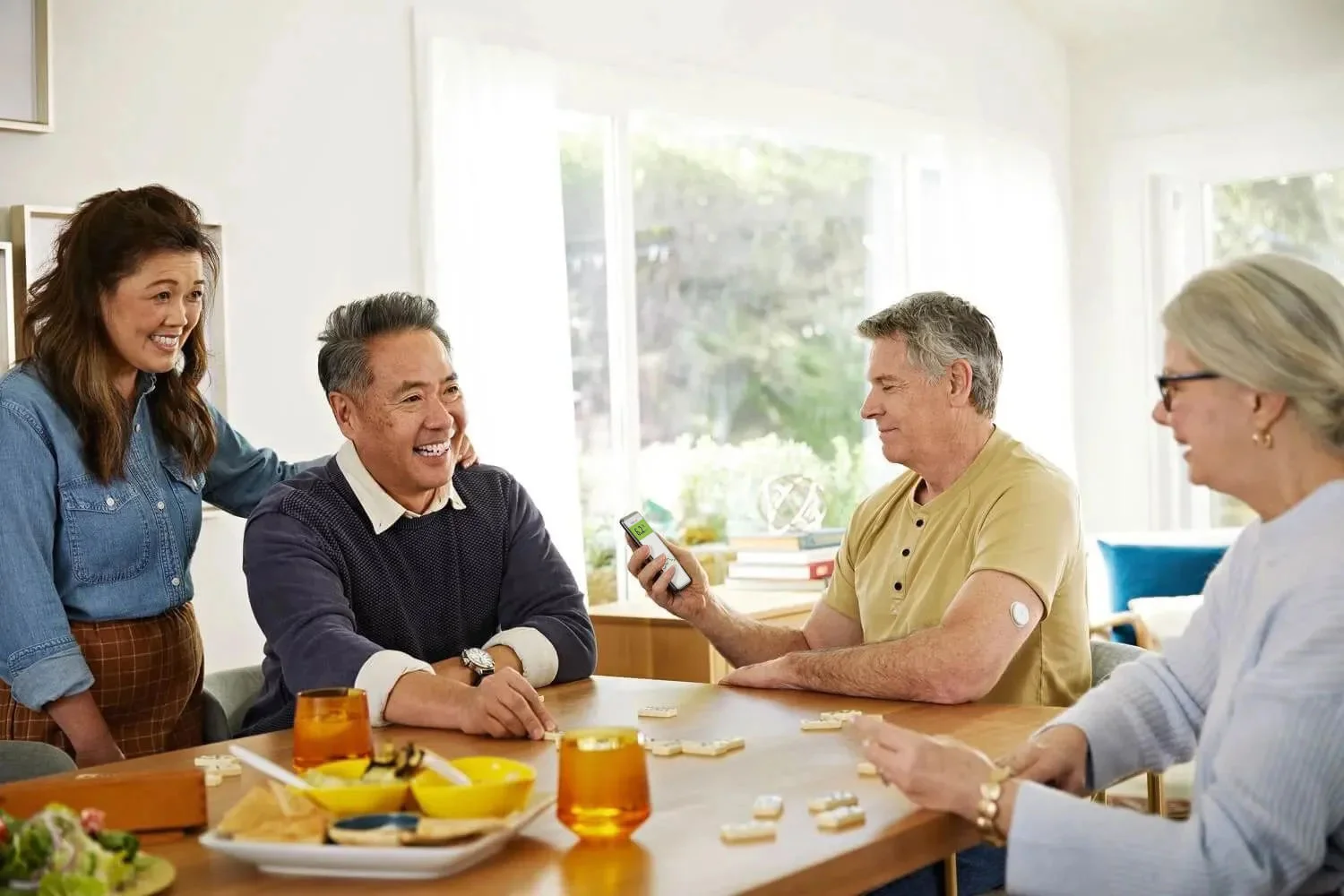 People gathered around a table discussing FreeStyle Libre, highlighting the referral program and earning store credits.
