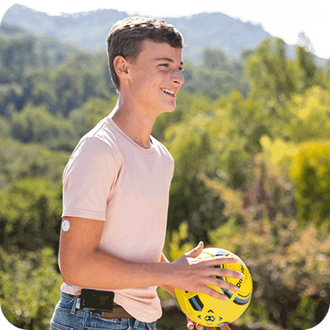 Child holding a ball while wearing a FreeStyle Libre 3 Plus sensor