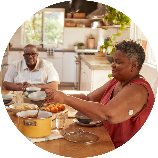 Mujer cocinando una comida saludable mientras utiliza el sensor FreeStyle Libre en el brazo