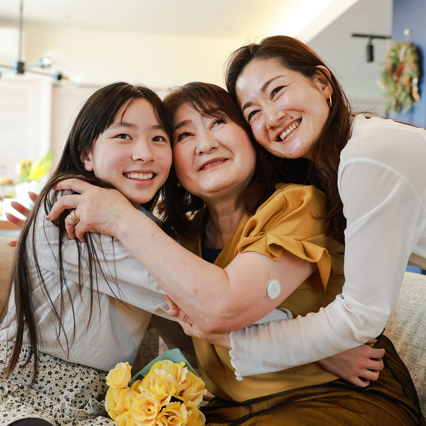 FreeStyle Libre glucose sensor visible on a person's upper arm during a close indoor gathering with two other people.