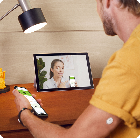 A man wearing a FreeStyle Libre sensor while speaking with his doctor on a tablet.