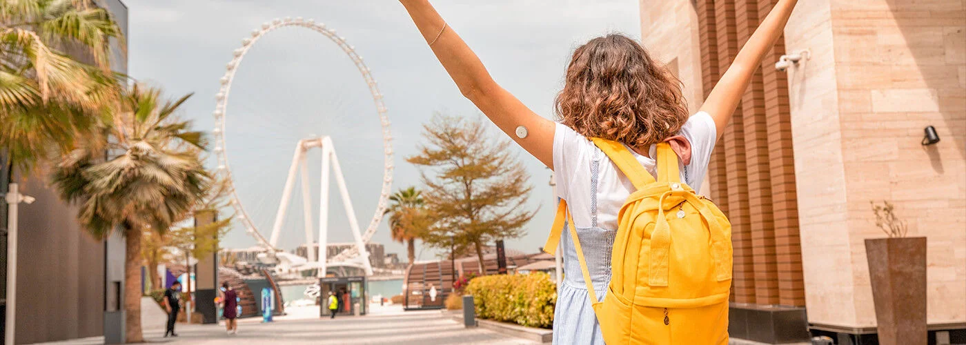 A imagem apresenta uma mulher de costas vestindo um vestido azul, com um sensor FreeStyle Libre2 Plus em seu braço