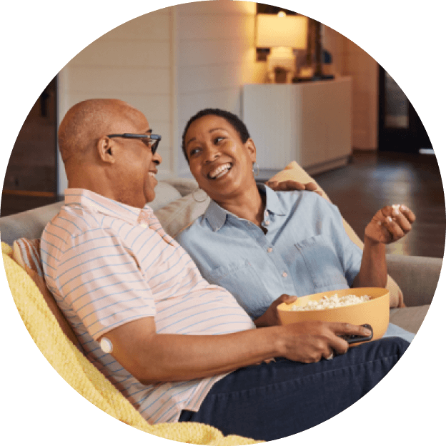 Pareja sentada en casa compartiendo palomitas de maíz, disfrutando un momento relajado y saludable.