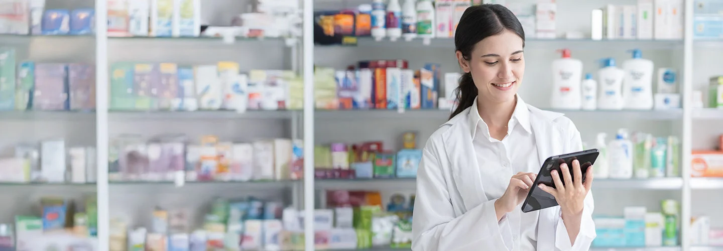 A pharmacist in a white jacket is talking with her customer about the FreeStyle Libre system which is sitting on the counter.