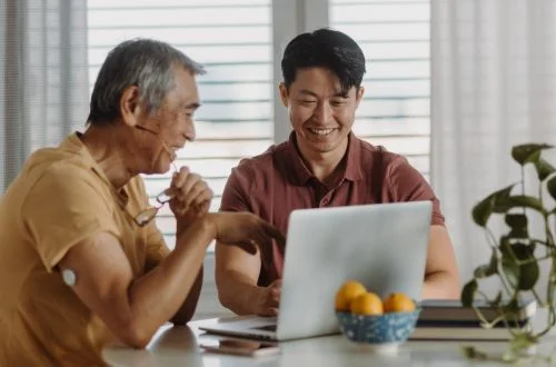 Son explaining to father using laptop