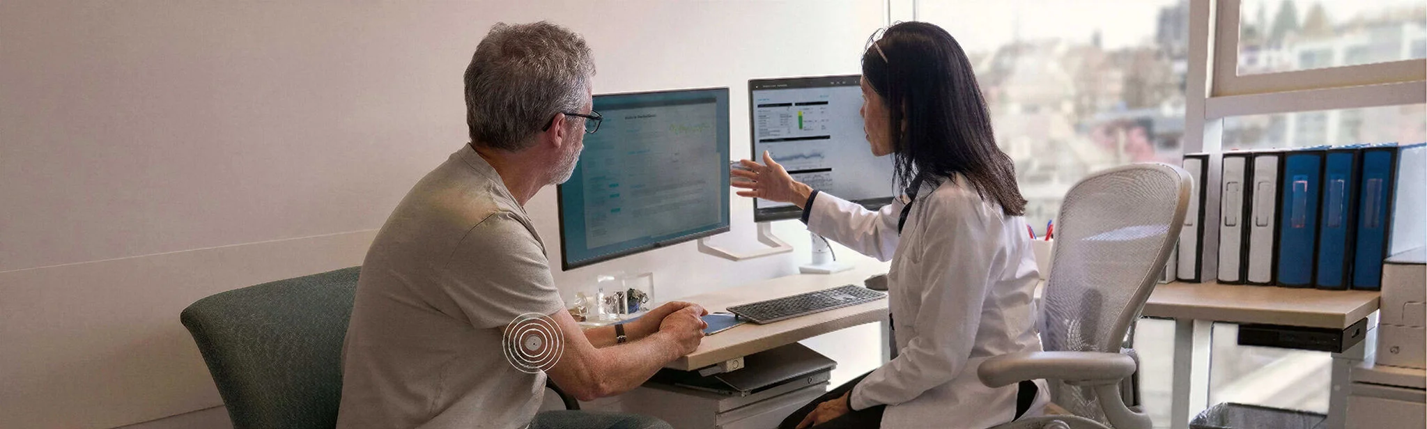 Médica e paciente analisam relatórios do LibreView durante consulta; o paciente usa o sensor FreeStyle Libre 2 Plus no braço.