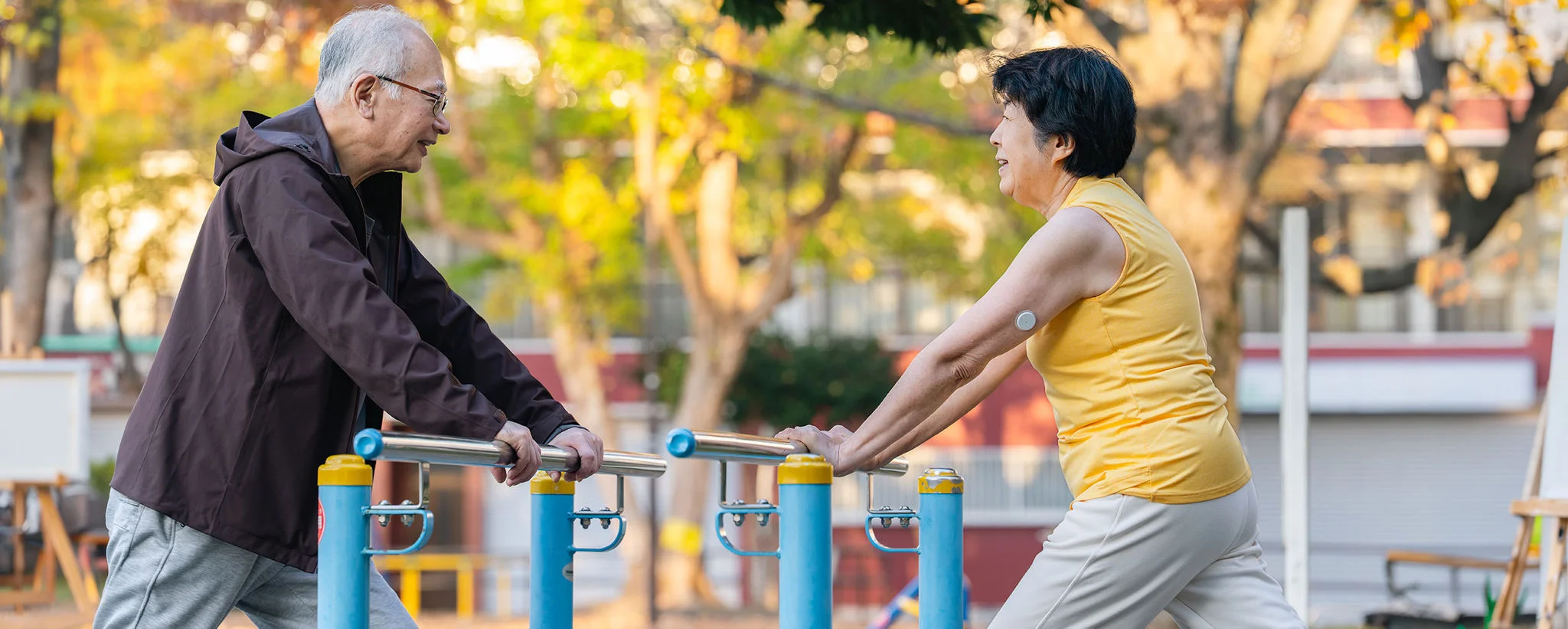 A woman wearing a sensor excercising in the park with her husband
