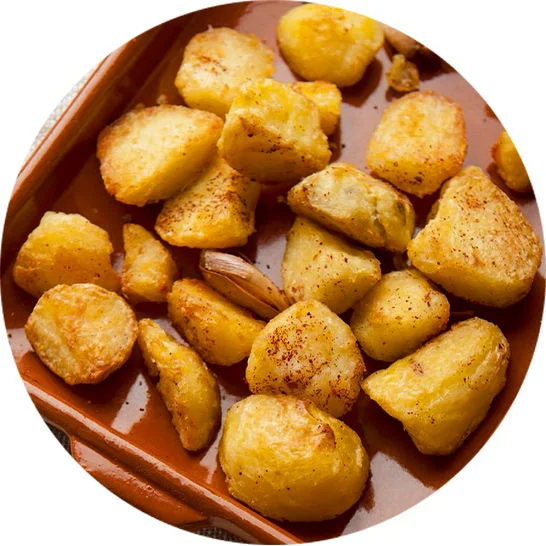Golden roasted potato chunks seasoned and served in a brown baking dish.