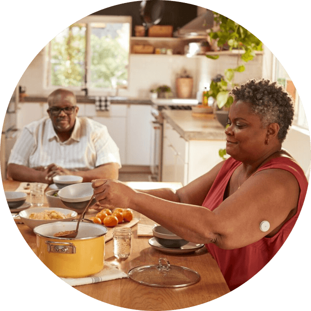 Mujer cocinando una comida casera mientras usa el sensor FreeStyle Libre en el brazo