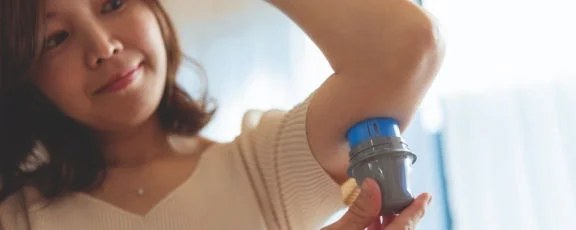 Person applying a Libre sensor under the upper arm using an applicator