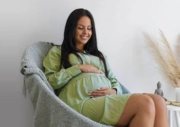 Pregnant woman rubbing her belly while sitting on a chair