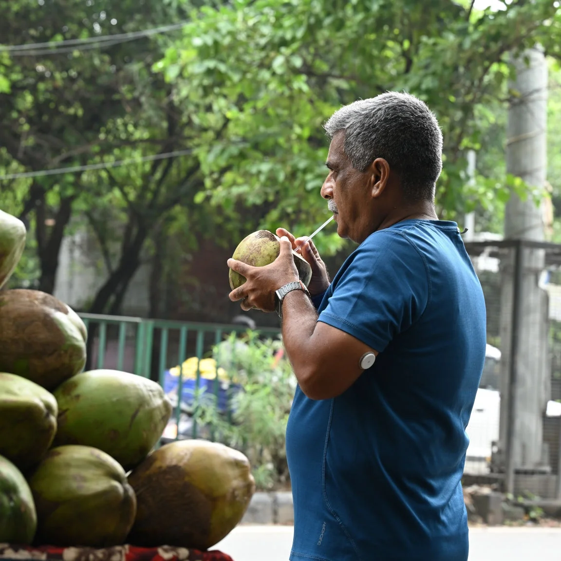 Man drinking outside with a glucose sensor on his arm.