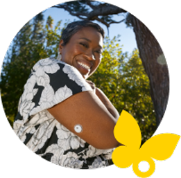 Woman smiling outdoors while wearing a FreeStyle Libre 3 Plus sensor
