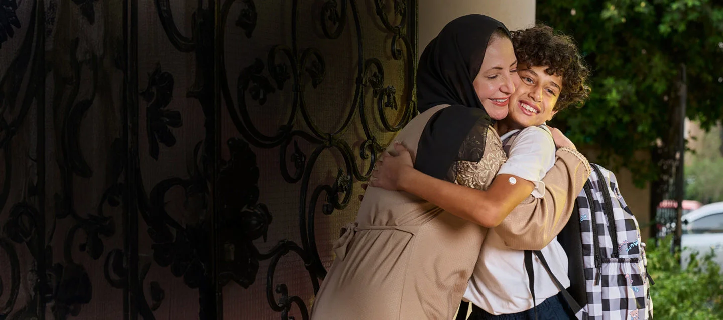 A boy wearing a freestyle libre sensor hugging his mom.