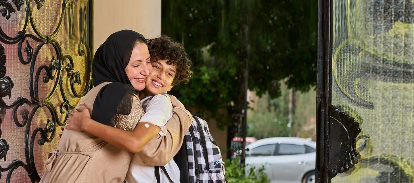 صبي يرتدي جهاز استشعار حر يعانق والدته.