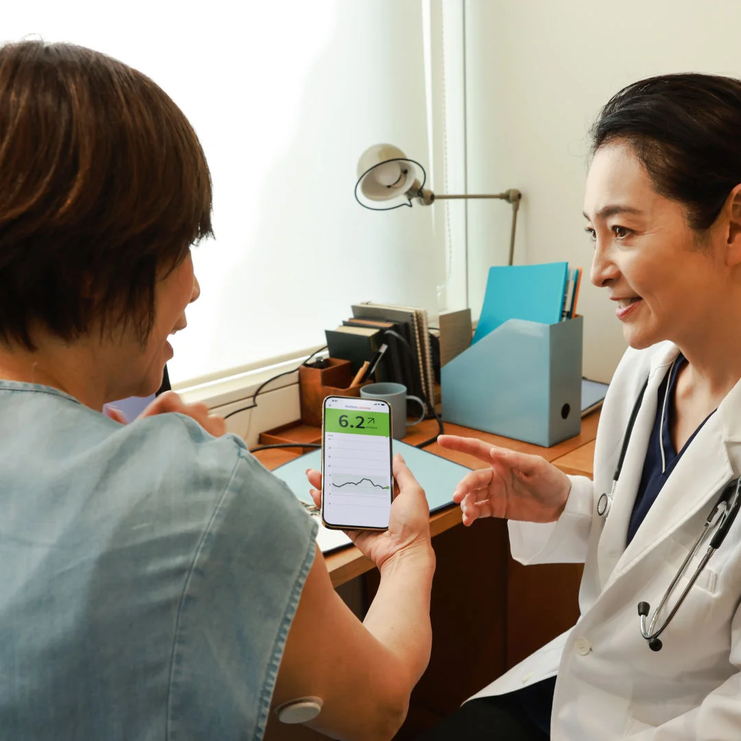 A man wearing a FreeStyle Libre sensor while speaking with his doctor on a tablet.