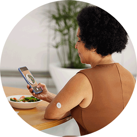 Woman taking a photo of her meal while wearing a FreeStyle Libre 3 Plus sensor