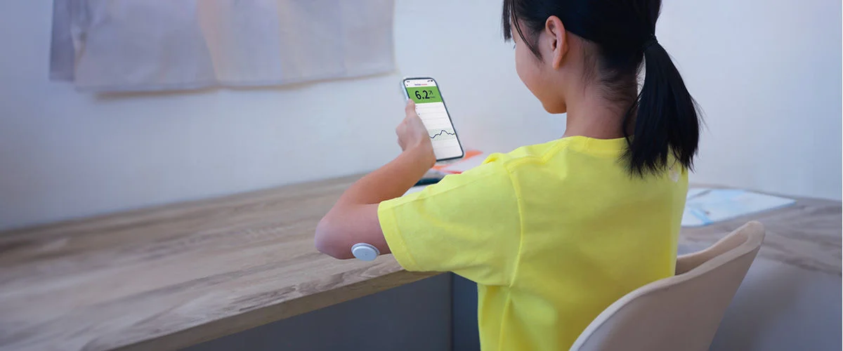 A Girl with sensor over shoulder watches app screen for readings