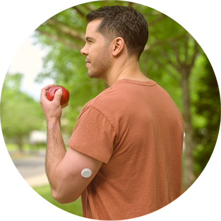 Man holding an apple while wearing a FreeStyle Libre 2 Plus sensor