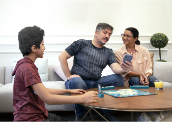 Pais conferindo os relatórios de glicose no celular com seu filho presente