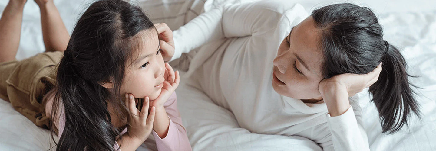 Mother laying next to her daughter on a bed