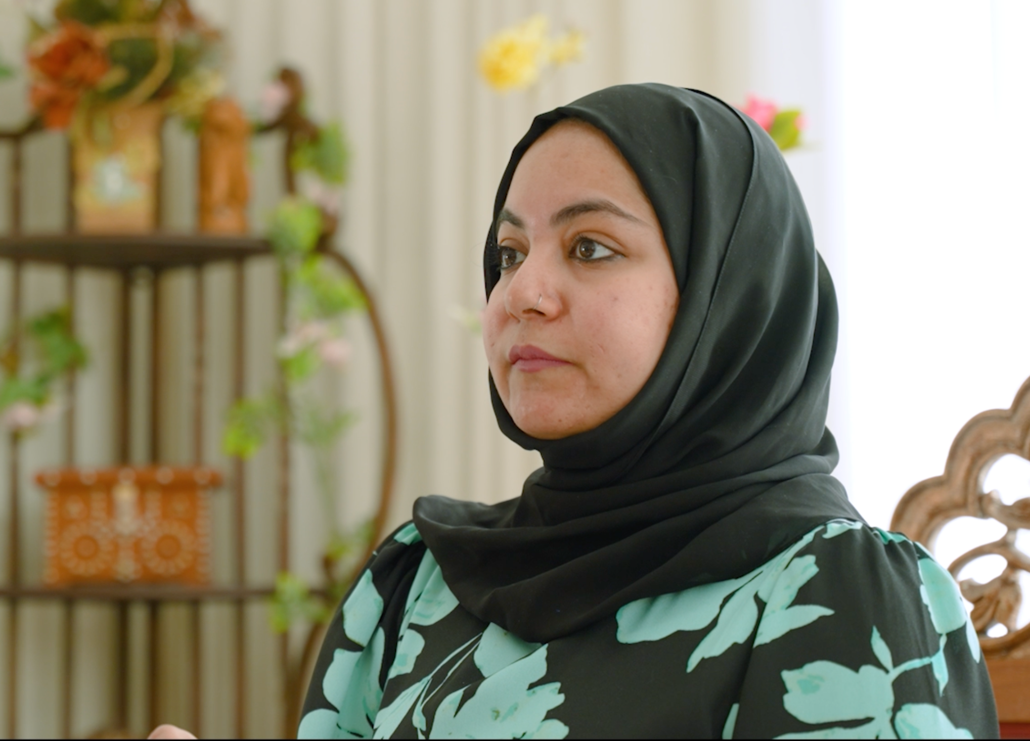 A woman wearing a sensor and holding her child in front of a fountain.