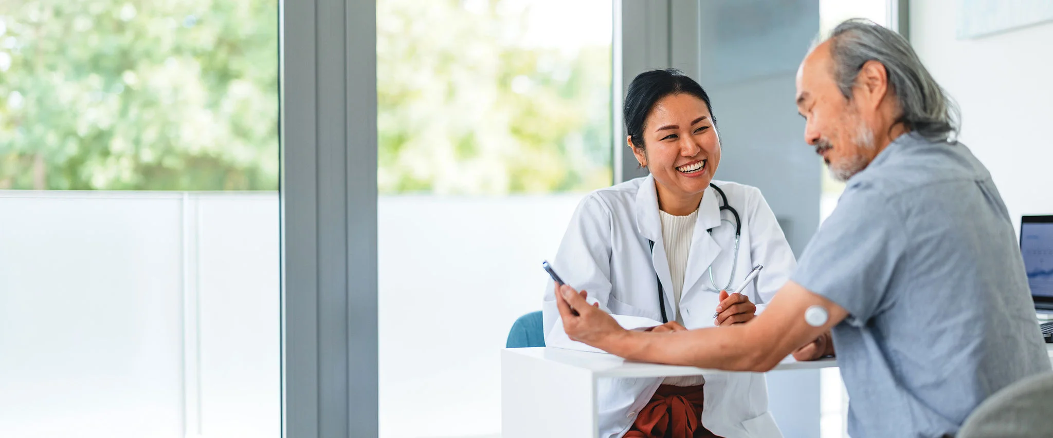 A man wearing a FreeStyle Libre sensor while speaking to his doctor in person.