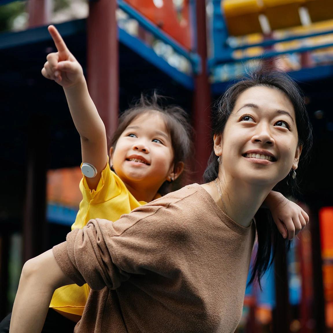 Mother and piggyback girl wearing a sensor in the playground