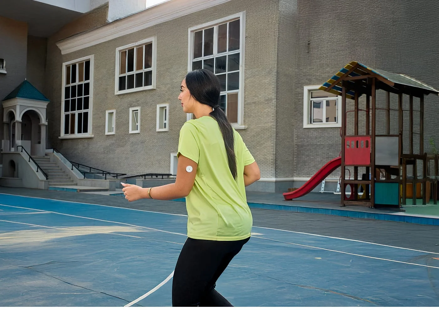 A woman running while wearing a FreeStyle Libre sensor.