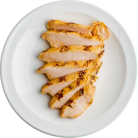 Sliced grilled chicken breast arranged on a white plate.