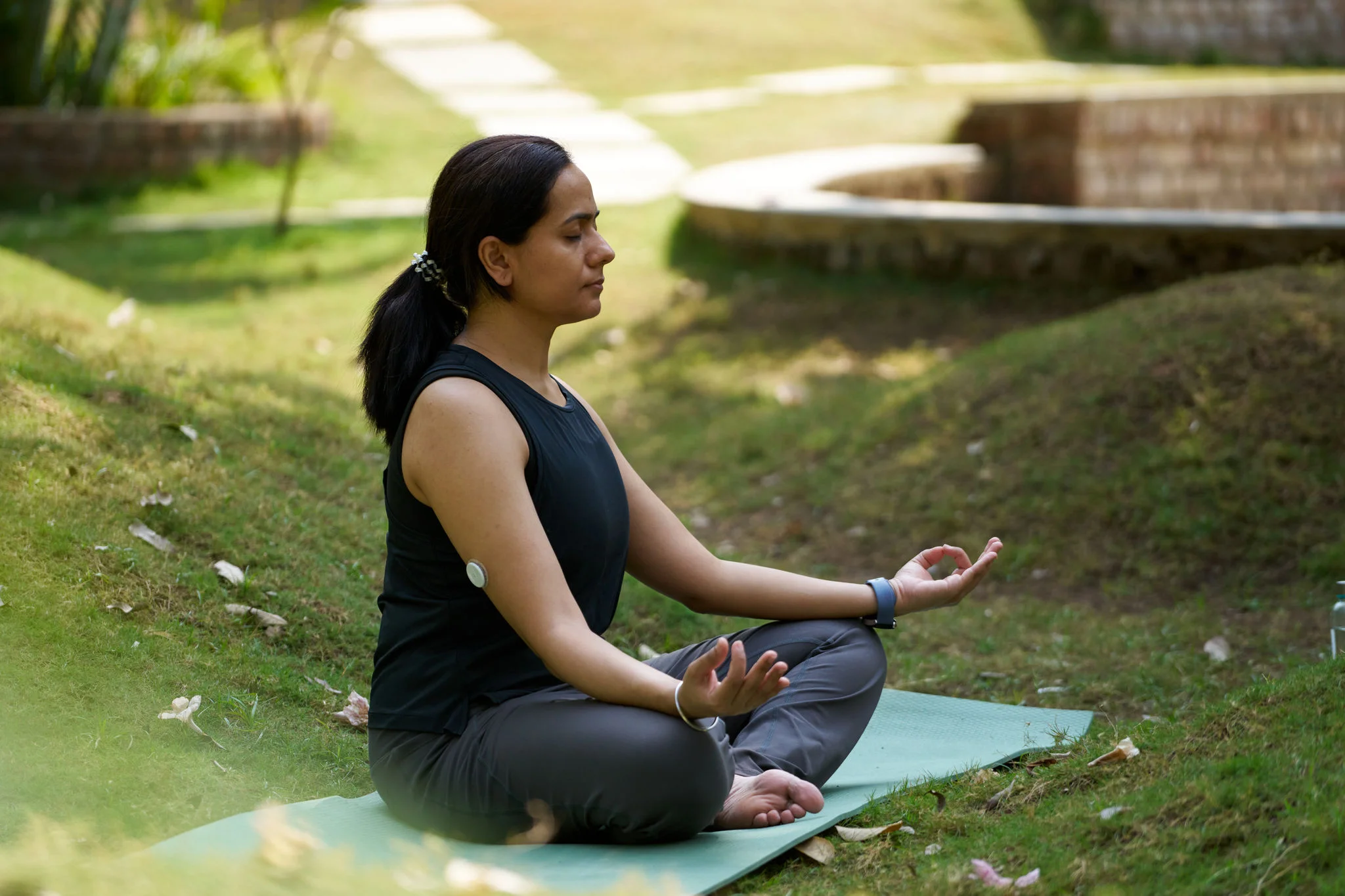 A woman wearing a FreeStyle Libre sensor  kneeling in front of her dog.
