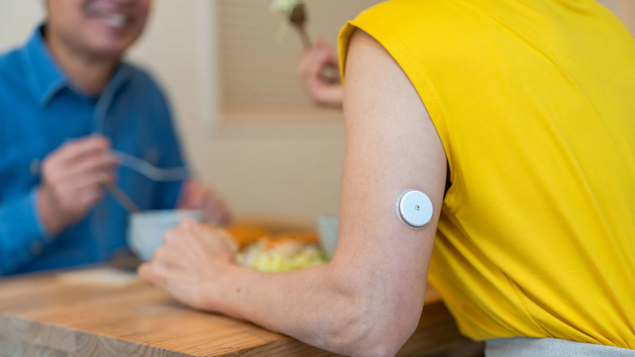 Person applying adhesive bandage to another person's arm.