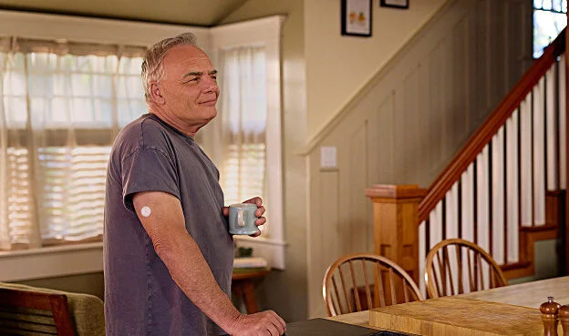 Hombre sonriendo en casa mientras usa el sensor FreeStyle Libre, mostrando confianza y bienestar