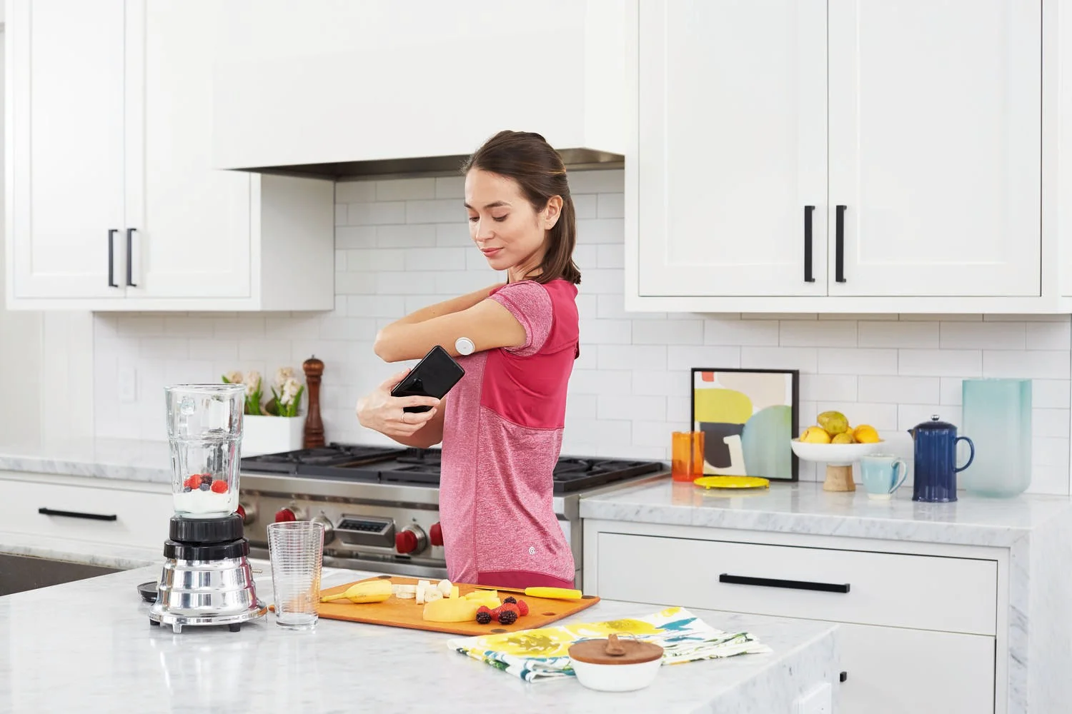 Pessoa em cozinha utiliza o sensor FreeStyle Libre 2 Plus aplicado no braço para acompanhar os níveis de glicose.