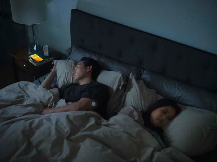 Person wearing FreeStyle Libre sensor checking glucose levels on their phone after waking up.