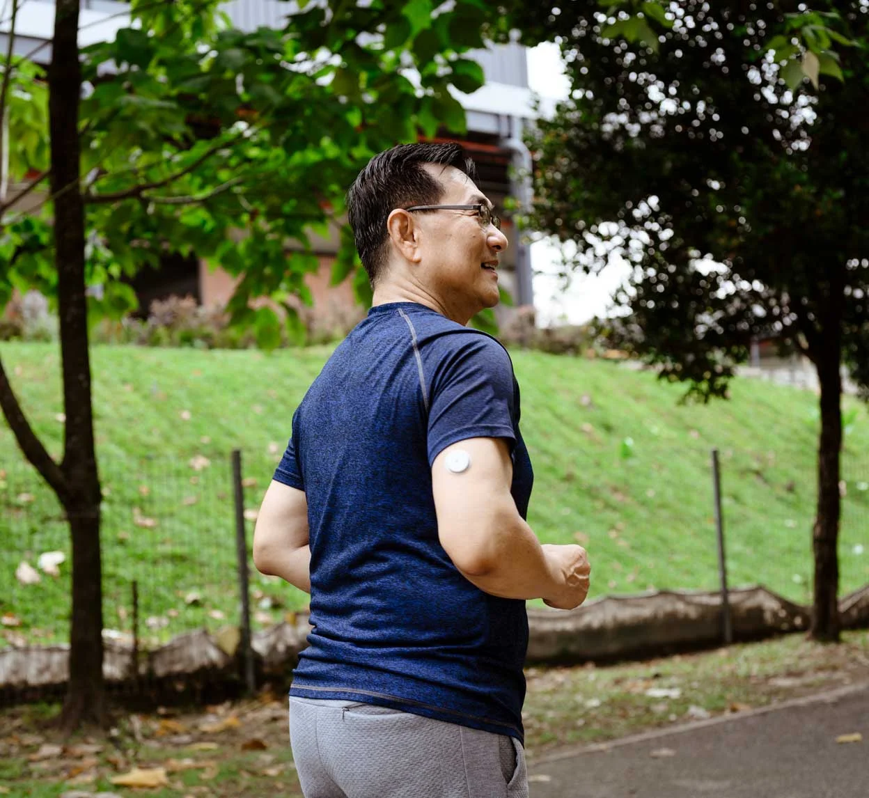Person jogging in a park wearing a glucose monitor, illustrating exercise to help manage stress and diabetes.