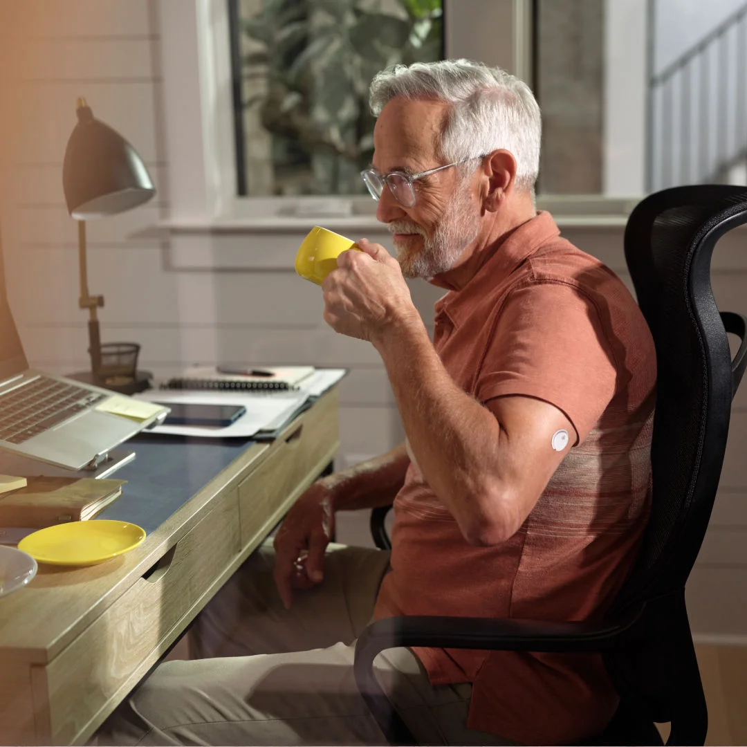 Mand ved skrivebord med sensor drikker kaffe