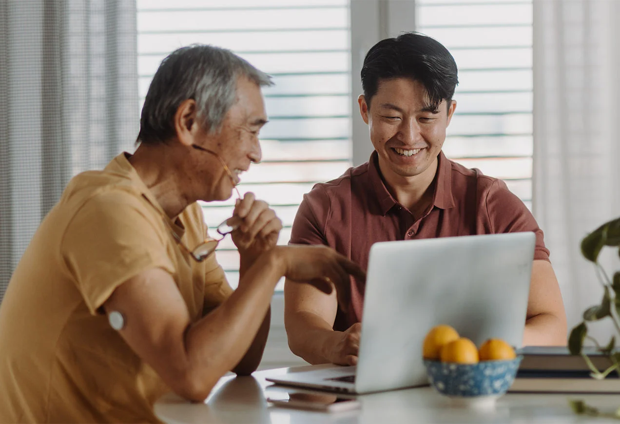 Người đàn ông cao tuổi đeo cảm biến đang trò chuyện với người chăm sóc.
